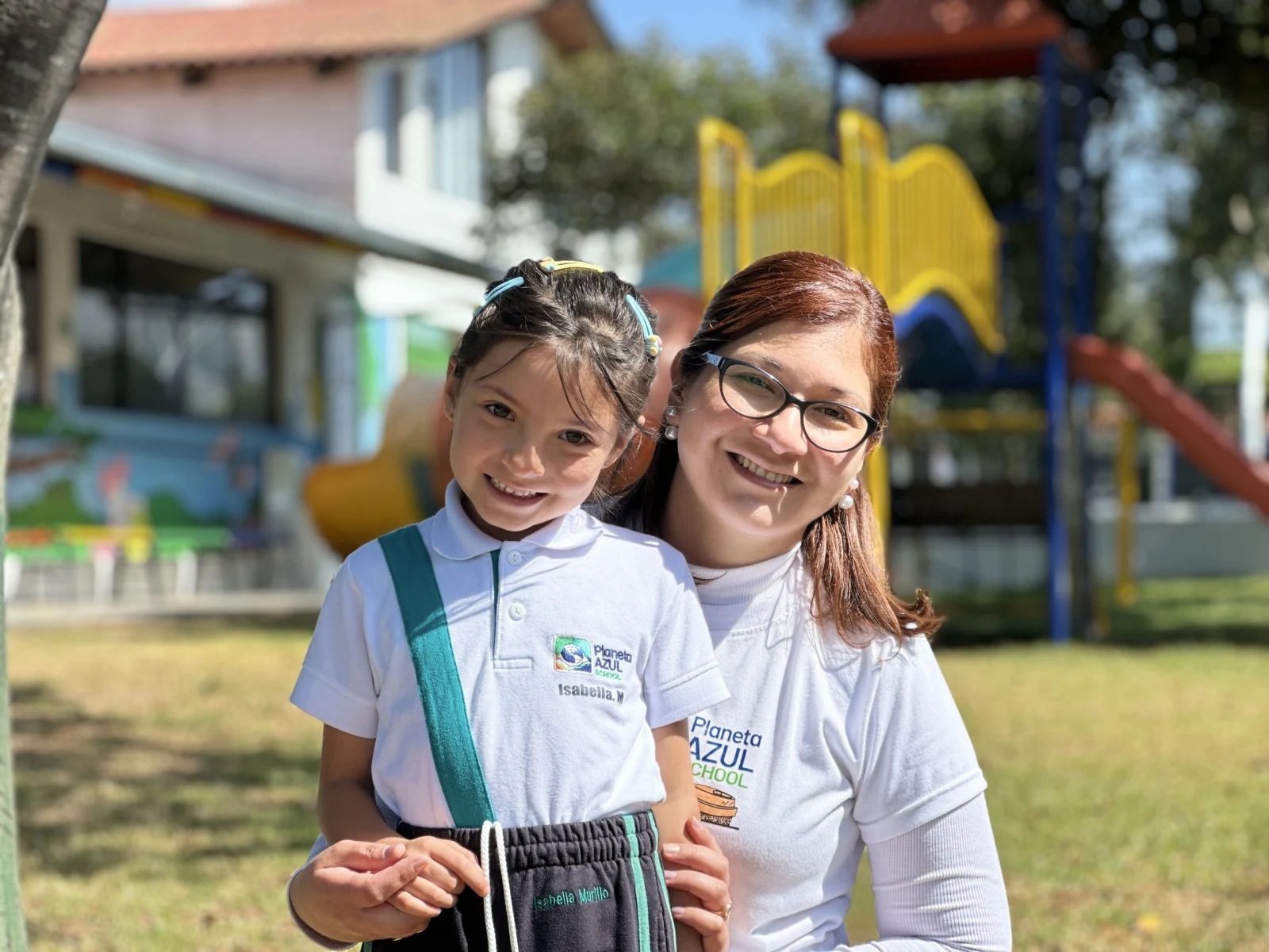 Una niña y una adulta de la comunidad Planeta Azul en el jardín del colegio